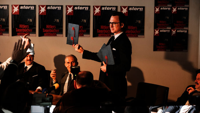 Faking Hitler: Pressekonferenz in der Stern Redaktion: Gerd Heidemann (Lars Eidinger) präsentiert die Hitler Tagebücher und liest aus ihnen vor. Bild: Sender / RTL / Martin Valentin Menke
