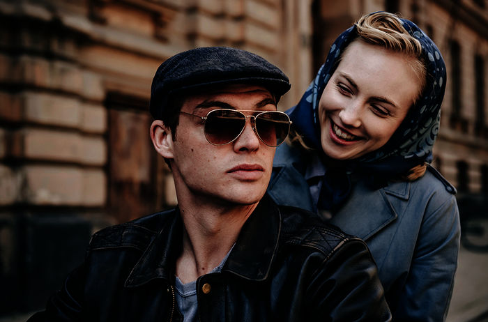 Ulla Wolf (Elisa Schlott) strahlt Tommy Weidner (David Schütter) an, als sie hinter ihm auf dem Motorrad sitzt. Bild: Sender / WDR / UFA Fiction / Willi Weber