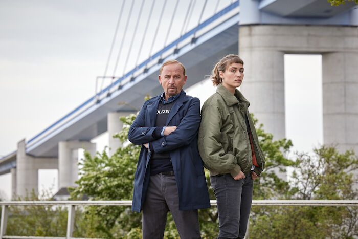 Stralsund: Ab 2023 gehen sie gemeinsam auf Verbrechersuche: Karl Hidde (Alexander Held) und die neue Kommissarin Jule Zabek (Sophie Pfennigstorf)- hier vor der Rügenbrücke. Bild: Sender / ZDF / Sandra Hoever.