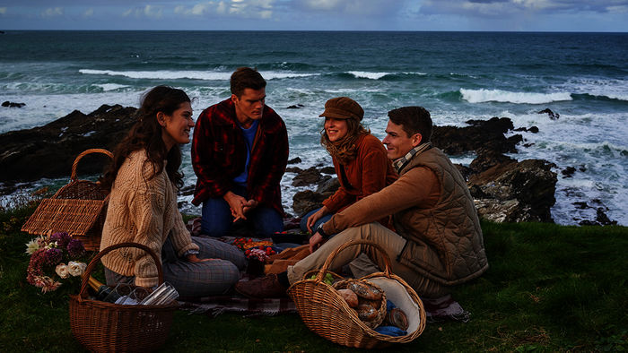 Abigail (Caroline Hartig) und ihre Schwester Doreen Collins (Leonie Brill) lernen Mo Miller (Paul Triller), den Kameraden und Freund von Bill Pexton (Marvin Linke) bei einem gemeinsamen Picknick an der Küste kennen. Doch Abigail und Mo kennen sich bereits, was sie den anderen jedoch verschweigen. Bild: Sender /  ZDF / Jon Ailes. 