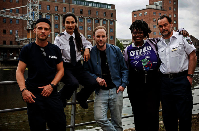 WaPo Duisburg:  Frank van Dijk (Niklas Osterloh), Arda Turan (Yasemin Cetinkaya), Regisseur Matthias Koßmehl, Lena Preser (Romy Vreden) und Gerhard Jäger (Markus John). Bild: Sender / ARD / Martin Valentin Menke