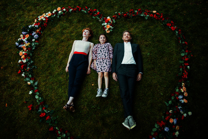 Deadlines: Lena (Sarah Bauerett), ihre Pflegetochter Talisa (Filippa Möller) und ihr Verlobter Marek (Markus “Maeckes” Winter) machen das Foto für ihre Hochzeitseinladungskarte. Dafür liegen sie auf dem Rasen, in einem Herz aus Rosen. Bild: Sender / ZDF und Anne Wilk.